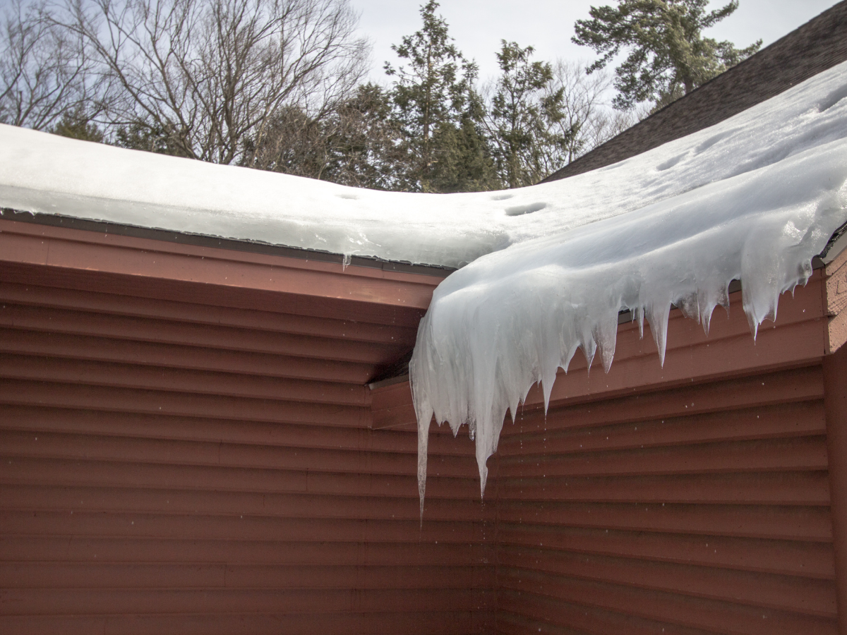 Ice dam on roof edge with snow on roof and icicles.